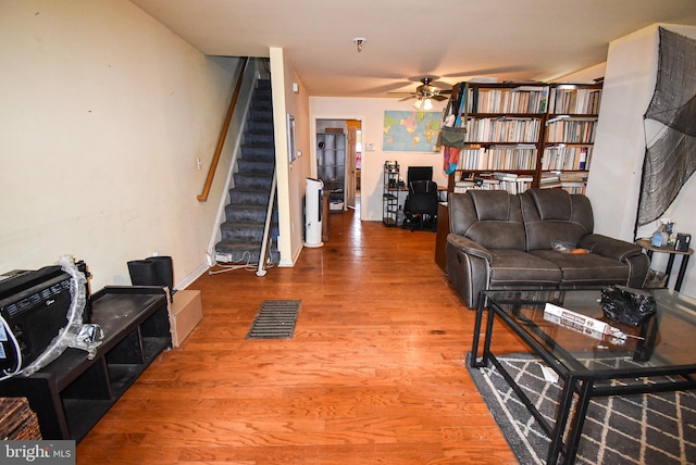 living area featuring stairs, ceiling fan, wood finished floors, and visible vents