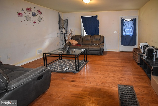 living room featuring wood finished floors, visible vents, and baseboards