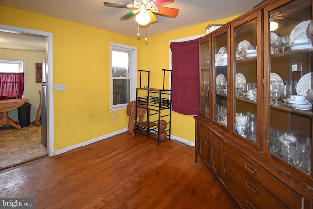 interior space with wood finished floors, a ceiling fan, and baseboards