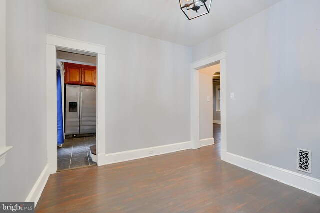 unfurnished room featuring arched walkways, dark wood finished floors, baseboards, and a chandelier