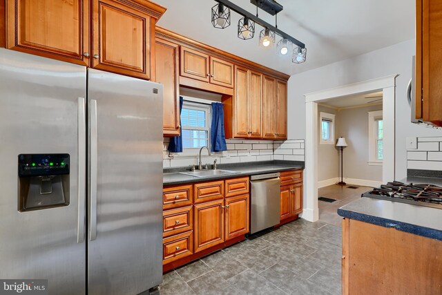 kitchen with appliances with stainless steel finishes, a sink, decorative backsplash, and brown cabinets
