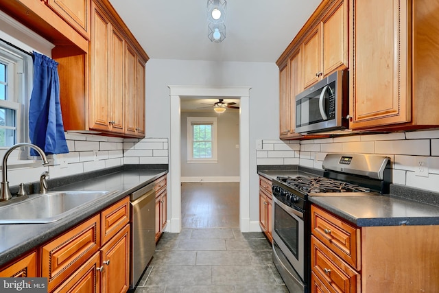 kitchen with appliances with stainless steel finishes, a sink, dark countertops, and brown cabinets