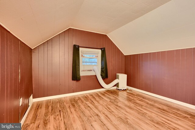 bonus room with wood finished floors, vaulted ceiling, and wooden walls