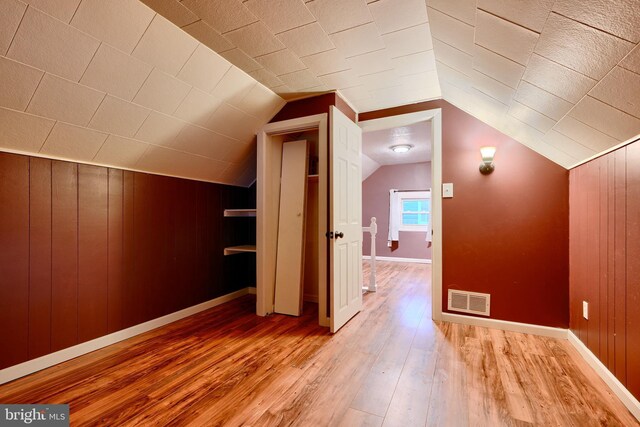 additional living space with light wood finished floors, baseboards, and vaulted ceiling