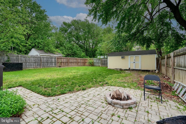 view of yard featuring a patio, a storage unit, a fire pit, and an outdoor structure
