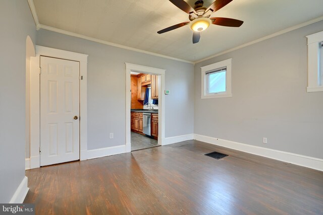 spare room with dark wood-type flooring, ceiling fan, baseboards, ornamental molding, and a sink
