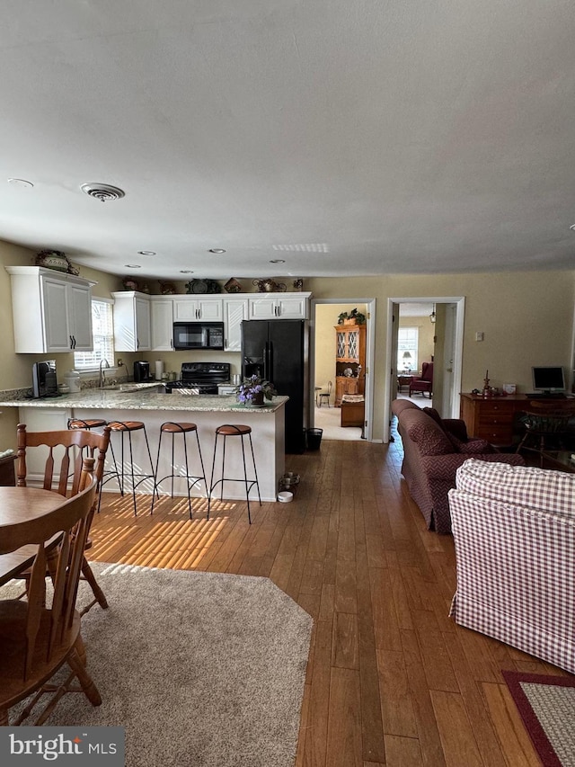 living area with dark wood-style floors and visible vents