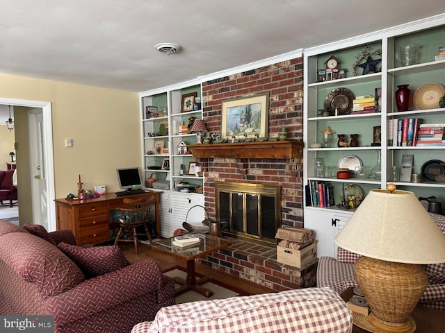 living area featuring a brick fireplace, built in shelves, and visible vents