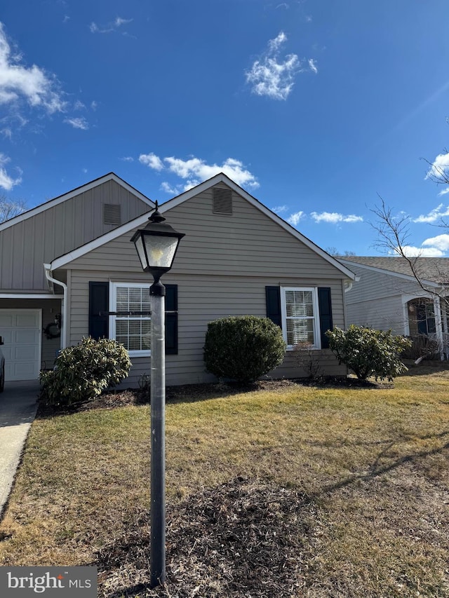 single story home with a garage, board and batten siding, and a front yard