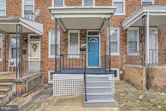 property entrance with covered porch and brick siding