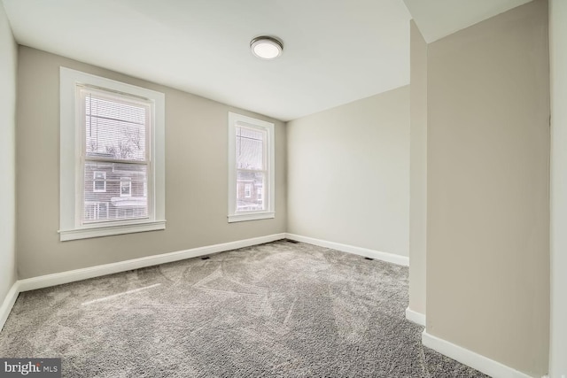 empty room featuring plenty of natural light, baseboards, and carpet flooring