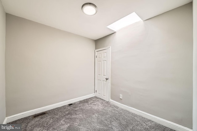 unfurnished room with carpet, a skylight, visible vents, and baseboards