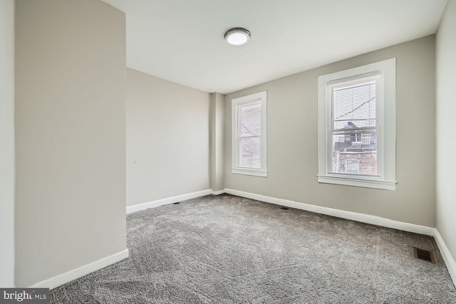 carpeted empty room featuring visible vents and baseboards