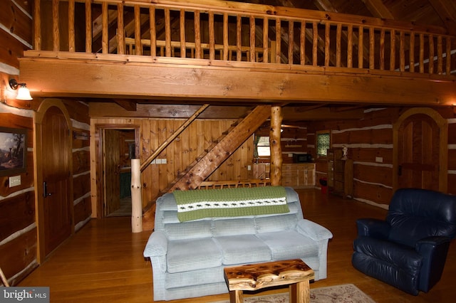 unfurnished living room featuring stairs, wood finished floors, and wooden walls