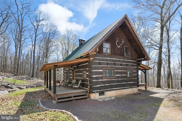 view of property exterior with a chimney, metal roof, and a deck