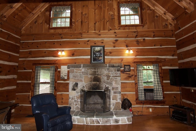 living room featuring high vaulted ceiling, a stone fireplace, wood walls, and wood finished floors