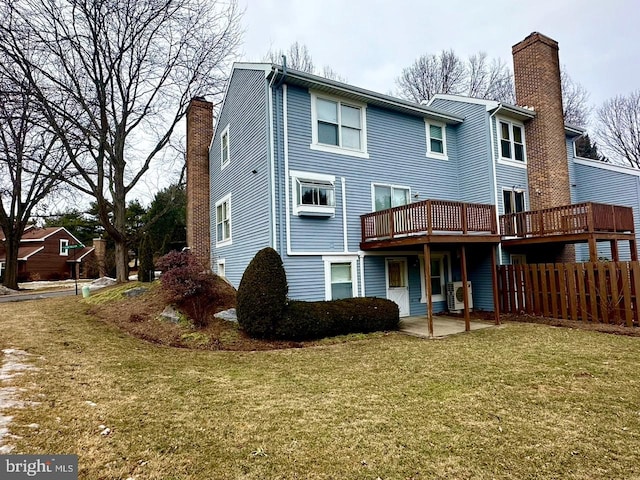 rear view of house featuring a yard, a chimney, and fence