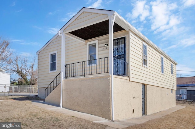 view of front of house featuring stairway, fence, and stucco siding