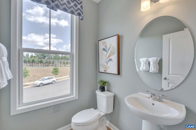 half bathroom with toilet, baseboards, and a sink