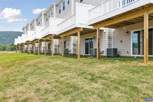 back of property with a wooden deck, central AC, and a yard