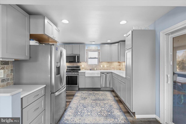 kitchen featuring stainless steel appliances, light countertops, dark wood finished floors, and tasteful backsplash