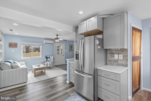 kitchen featuring open floor plan, a wall mounted air conditioner, gray cabinetry, and stainless steel fridge with ice dispenser