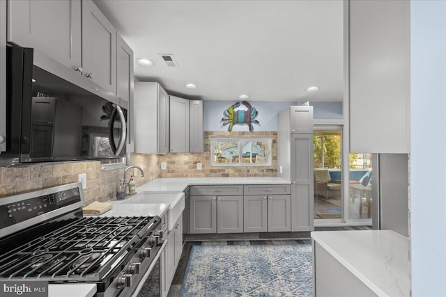 kitchen featuring light countertops, appliances with stainless steel finishes, visible vents, and tasteful backsplash