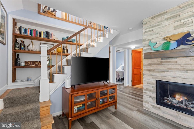 living area featuring a fireplace, stairway, and wood finished floors