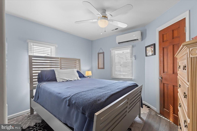 bedroom featuring baseboards, visible vents, ceiling fan, wood finished floors, and an AC wall unit