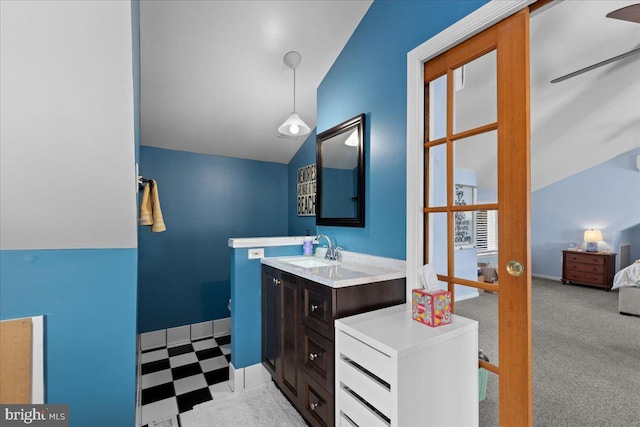 ensuite bathroom featuring vaulted ceiling, vanity, baseboards, and tile patterned floors