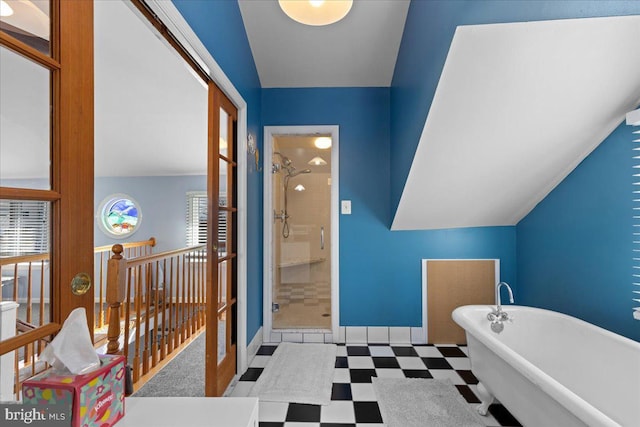 full bath featuring baseboards, tile patterned floors, vaulted ceiling, a freestanding bath, and a shower stall