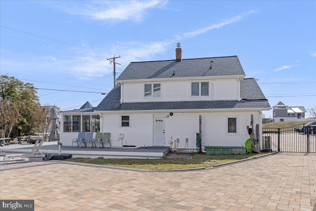 rear view of house featuring a gate, roof with shingles, a patio, and a chimney