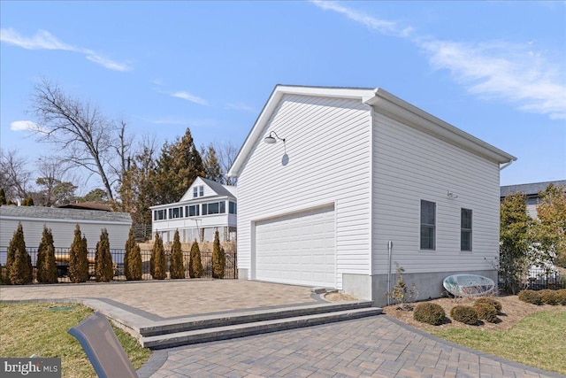 view of property exterior with a garage, driveway, and fence