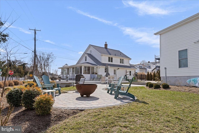 rear view of house featuring a patio, a lawn, fence, and a sunroom