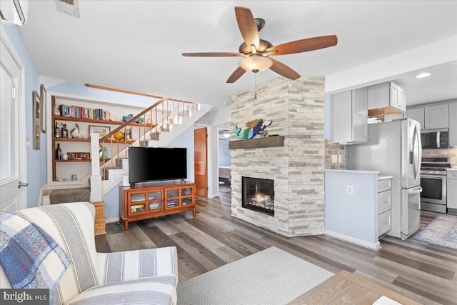 living area featuring visible vents, a fireplace, stairway, and wood finished floors