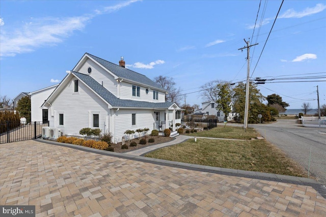 view of front facade with ac unit, a chimney, a shingled roof, fence, and a front lawn