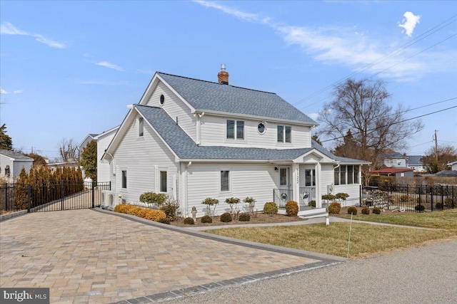 view of front of property with a chimney, a shingled roof, a front yard, a gate, and fence