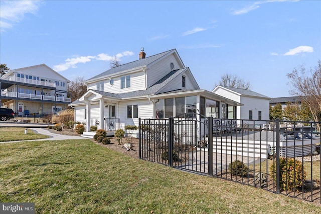 view of front facade featuring a sunroom, a chimney, fence, and a front lawn