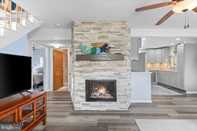 living room with a healthy amount of sunlight, a stone fireplace, and wood finished floors