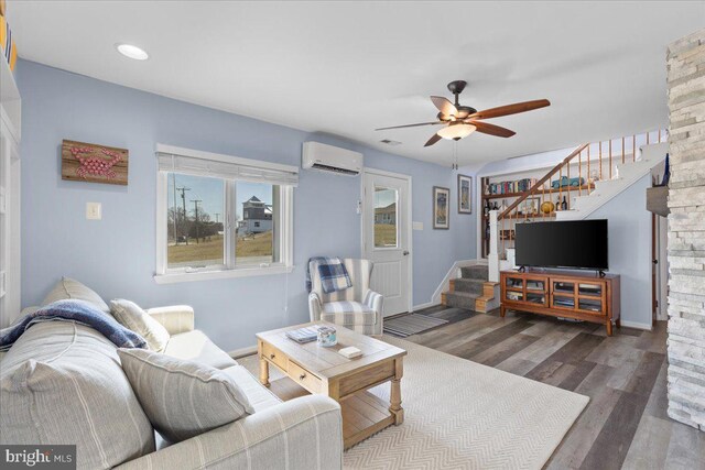 living area with stairway, a ceiling fan, wood finished floors, a wall mounted air conditioner, and baseboards