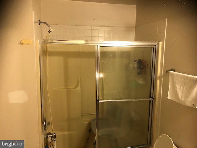 bathroom featuring a shower with door and toilet