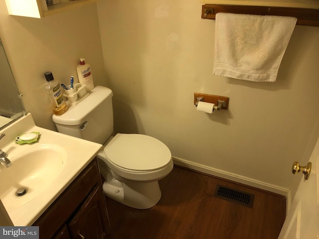 bathroom with toilet, wood finished floors, vanity, visible vents, and baseboards