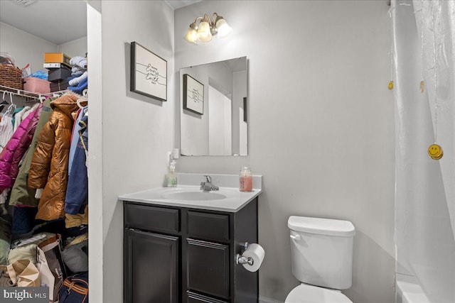 full bath featuring vanity, a shower with shower curtain, a spacious closet, toilet, and a washtub