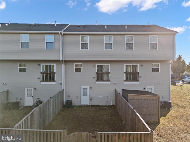 rear view of house with central AC and fence