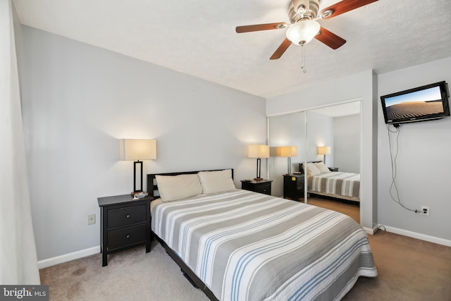 carpeted bedroom with ceiling fan, baseboards, and a textured ceiling