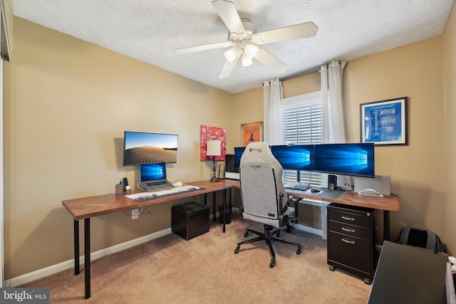 office area featuring baseboards, light colored carpet, ceiling fan, and a textured ceiling