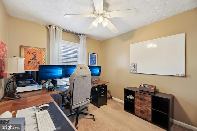 carpeted office space featuring baseboards, a textured ceiling, and ceiling fan