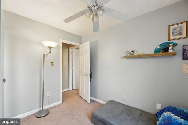 living area with baseboards, carpet floors, and a ceiling fan