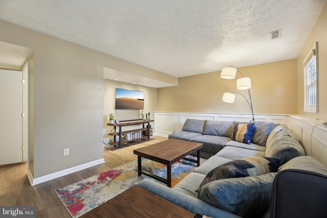 living room featuring wood finished floors, a wainscoted wall, and a textured ceiling