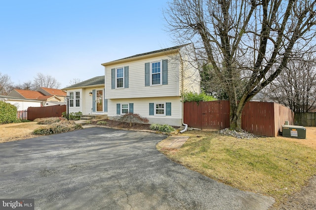 tri-level home featuring a front yard and fence